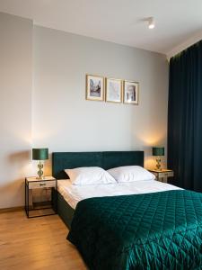 een slaapkamer met een groen bed en 2 nachtkastjes bij Warsview Apartments in Warschau