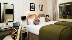 ロンドンにあるホテル・キセニア、オートグラフ コレクションのベッド2台、デスク、鏡が備わる客室です。