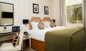 1 dormitorio con cama, escritorio y ventana en Hotel Xenia - Autograph Collection, en Londres