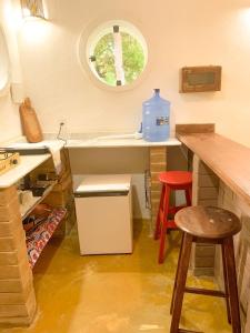 uma cozinha com um lavatório e um balcão com dois bancos em Chalé Nova Terra em Imbassaí