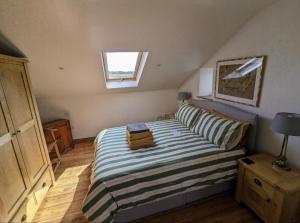 a bedroom with a bed with a striped comforter and a window at Treverrows Barn - Barn Conversion on the Farm in Penryn