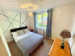 Schlafzimmer mit einem Bett und einem Fenster in der Unterkunft Spacious 3-Bedroom Ground Floor Flat with Free Parking in Central Location in Cardiff