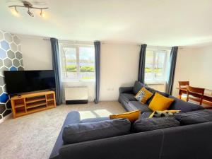 ein Wohnzimmer mit einem blauen Sofa und einem Flachbild-TV in der Unterkunft Spacious 3-Bedroom Ground Floor Flat with Free Parking in Central Location in Cardiff