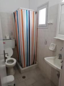 a bathroom with a striped shower curtain and a toilet at Christina Pension in Karterados