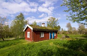 mały czerwony dom na trawiastym polu w obiekcie STF Tivedstorp w mieście Tivedstorp