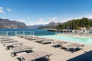 a dock with lounge chairs and a swimming pool at Araba Fenice Hotel in Iseo