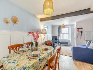 a dining room with a table and a blue couch at Primrose Cottage in Teignmouth