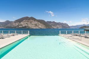 a swimming pool with chairs and a body of water at Araba Fenice Hotel in Iseo