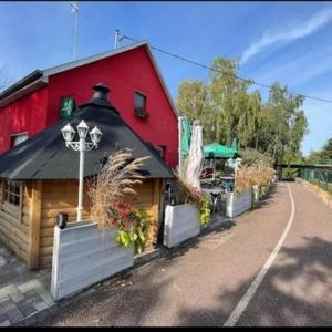 ein rotes Gebäude mit schwarzem Dach neben einer Straße in der Unterkunft Au Hameau de l'Ecluse proche Europa-Park in Marckolsheim