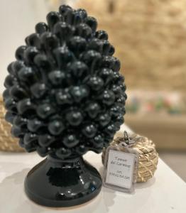 a black vase filled with black balls on a table at Tannur Del Carmine in Noto
