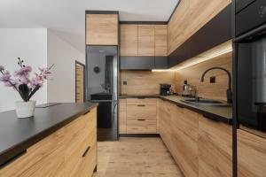 a kitchen with wooden cabinets and a black counter top at Apartment with 2 Bedrooms & Parking Wrocław by Renters in Wrocław