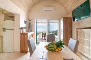 una cucina e una sala da pranzo con tavolo e cesto di frutta di VILLA Alessandra a Marina di Pescoluse