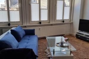 a living room with a blue couch and a glass table at Ferienwohnung Marktblick Goslar in Goslar +34 photos