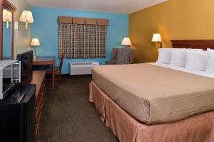 a hotel room with a bed and a desk and a television at Americas Best Value Inn - Seymour in Seymour