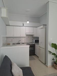 a kitchen with white cabinets and a couch in it at δίπλα στο πάρκο in Kalamata