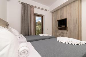 a hotel room with two beds and a television at Claudio Stone House in Vasilikos +27 photos