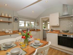 a kitchen with a wooden table with flowers on it at Pool Cottage in Hereford