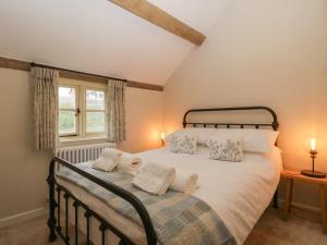 a bedroom with a bed with white sheets and pillows at Pool Cottage in Hereford