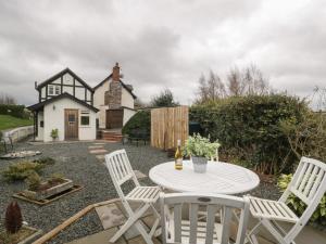 eine Terrasse mit einem weißen Tisch und Stühlen vor einem Haus in der Unterkunft Pool Cottage in Hereford