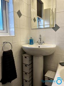 La salle de bains est pourvue d'un lavabo et d'un miroir. dans l'établissement Cosy Home with links to B'ham, Solihull, NEC, M42, à Sheldon