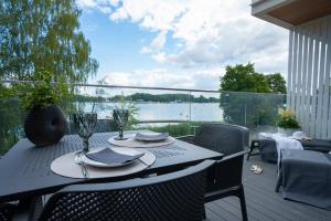 a table and chairs on a deck with a view of the water at Olimpijska Premium by RENT4YOU in Olsztyn