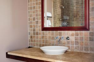 a bathroom with a sink and a mirror on a counter at The Harbor Front Inn in Greenport