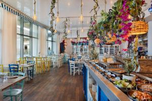 restauracja ze stołami i krzesłami oraz stanowiskiem z jedzeniem w obiekcie West Tel Aviv- All Suites Hotel By The Sea w Tel Awiwie