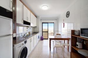 a kitchen with white cabinets and a table and a dining room at Apartamento Serra e Mar in Alvor