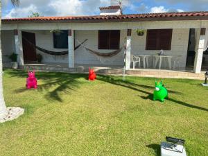 three plastic pigs sitting in the grass in front of a house at Casa Pé na Areia in São José da Coroa Grande
