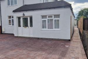 a small white house with white doors and a patio at 1 Bedroom Studio in Eltham