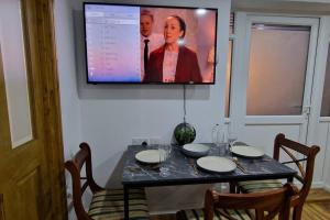 uma televisão pendurada numa parede acima de uma mesa com cadeiras em 1 Bedroom Studio em Eltham