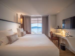 um quarto de hotel com uma cama, uma secretária e uma janela em Côté Thalasso Hôtel & Spa Marin em Banyuls-sur-Mer