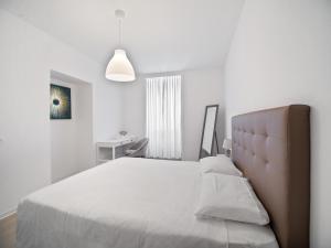 a white bedroom with a large bed and a lamp at Casa Cattaneo in Faido