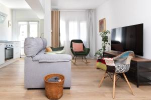 een woonkamer met een bank en stoelen en een tv bij MyHouseSpain - Acogedor piso nuevo en Gijón in Gijón