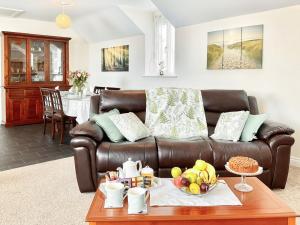 a brown leather couch in a living room with a table at Leddon Farm Annexe-uk39616 in Gooseham
