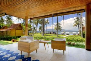a patio with a view of the ocean and palm trees at Villa So Long Banyuwangi - Ijen in Banyuwangi