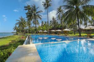 a swimming pool with palm trees and the ocean at Villa So Long Banyuwangi - Ijen in Banyuwangi