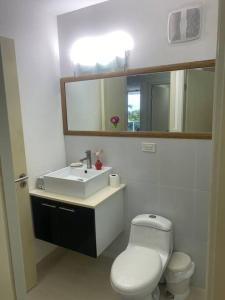 a bathroom with a white toilet and a sink at Bala Beach Paradise 1-bedroom Fully Equipped apt. in Colón