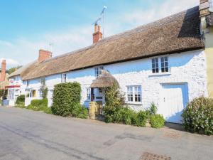 a white building with a thatched roof at Lime Cottage in Bridport