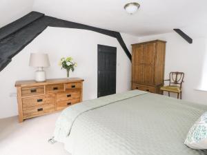 a bedroom with a bed and a wooden dresser and a table at Lime Cottage in Bridport