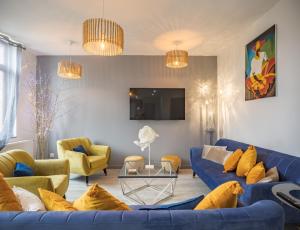 sala de estar con sofá azul y sillas amarillas en Le Joyau ! Brillant & Chic - Park. Privé - Premium, en Troyes