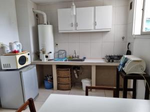 cocina con armarios blancos, fregadero y microondas en Departamento Mendoza Olascoaga 2 en Mendoza
