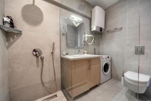a bathroom with a shower and a sink and a washing machine at City Apartments 2 in Budva