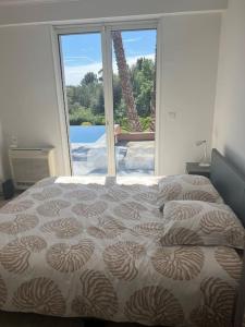ein Schlafzimmer mit einem Bett und einem großen Fenster in der Unterkunft Villa avec Piscines in Cagnes-sur-Mer