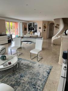 ein Wohnzimmer mit einem Tisch und weißen Stühlen in der Unterkunft Villa avec Piscines in Cagnes-sur-Mer