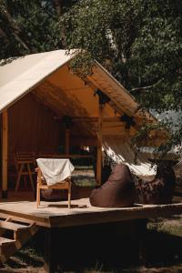 a tent with a chair and a hammock under it at Glamping Mandra Kanev in Leplyavo