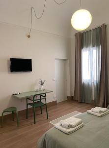 een kamer met 2 bedden, een tafel en een televisie bij La Casa di LiLù in Taranto