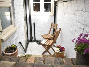 une chaise en bois assise sur une terrasse fleurie dans l'établissement Church View Cottage, à Ashbourne