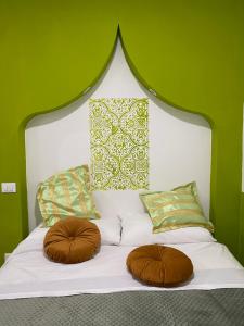 een wit bed met 2 kussens en een groene muur bij Dar Zohra in Pozzuoli