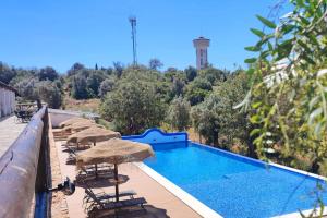 a swimming pool with chairs and umbrellas on a balcony at Monte das Fontainhas in Pêra